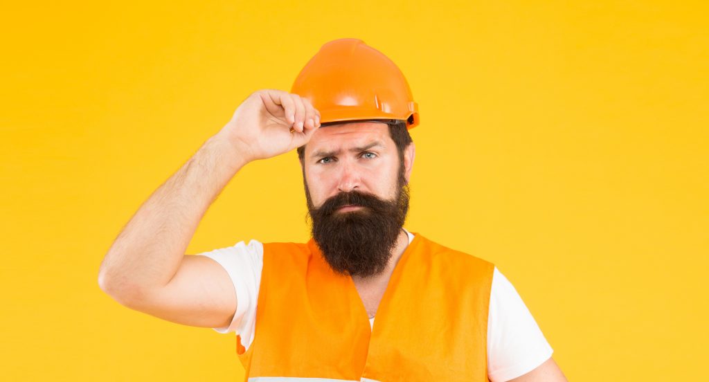 Labor day. Safety apparel for construction industry. Bearded brutal hipster safety engineer. Engineering career concept. Architect builder engineer. Man engineer protective uniform orange background